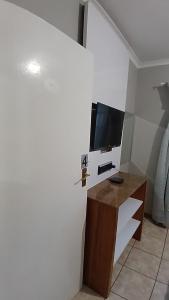 a living room with a tv on a stand with a desk at Maselli Guesthouse in Howick