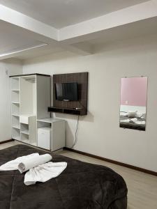 a bedroom with a bed and a flat screen tv at Pousada Centro in Gramado