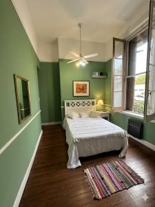 a green bedroom with a bed and a ceiling fan at Hotel Posada de 1860 in Tigre