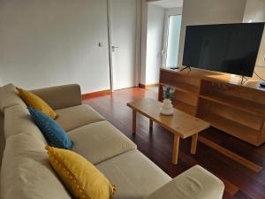 a living room with a couch and a flat screen tv at Residencias Requinte T3 Espacoso com Terraco e Vista in São Roque do Pico