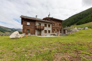 a house on a hill with a grass field at Chalet Ice Villa Genf Spa - Relax in Livigno