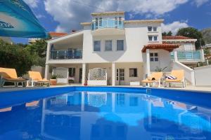 a villa with a swimming pool in front of a house at Apartment with Sunset terrace in Mlini