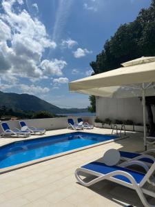a swimming pool with lounge chairs and an umbrella at Apartment with Sunset terrace in Mlini