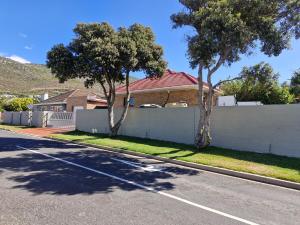 a house with a white fence and trees on a street at 77 on First! in Fish Hoek