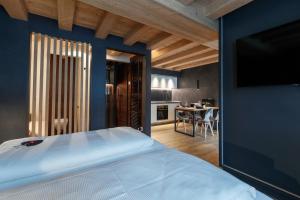 a bedroom with a white bed and a kitchen at Wind Villa Genf Spa - Relax in Livigno