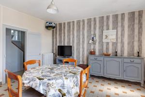 a dining room with a table and chairs and a television at Gîte Le Trotteur in Monteaux