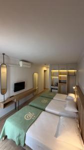 ein Zimmer mit drei Betten und einem Flachbildfernseher in der Unterkunft Rıdvan Hotel in Cesme + 43 Fotos