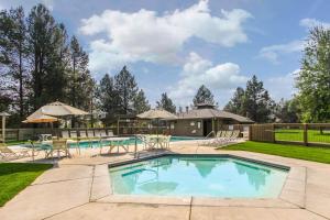 ein Swimmingpool mit Tischen und Stühlen in einem Garten in der Unterkunft 72 Quelah in Sunriver