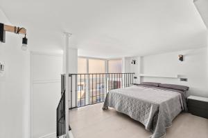 a white bedroom with a bed and a balcony at Vima Lofts in Torrevieja
