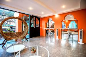 a room with orange walls and a chair and a table at Khaleej Mass Hotel Patong in Patong Beach
