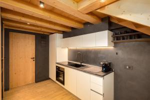 a kitchen with white cabinets and a sink and a wooden ceiling at Chalet River Villa Genf Spa - Relax in Livigno