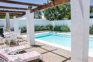 a pool with a table and chairs next to a house at De Kothuize 10 in Graaff-Reinet