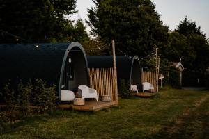 a group of chairs in a yard with a tent at Glamping Pod in de natuur Eigen badkamer in Oudehornstercompagnie