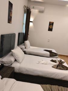 three beds in a room with white walls and a window at Karma Cairo Hotel in Cairo