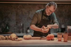 a man in a kitchen preparing vegetables on a counter at Huis De Mijmering in Heikant +6 photos