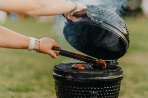 a woman cooking food on a grill at Glamping Pod in de natuur Eigen badkamer in Oudehornstercompagnie