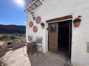 a white building with a door and two chairs at Casa Buena Vista in Ugíjar