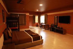 a bedroom with a bed and a flat screen tv at The Den by Trees in Kotagiri