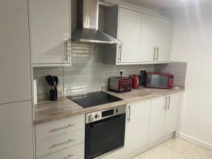 a kitchen with white cabinets and a sink and a microwave at Charming Contractors & Family Friendly 3-BR House in Harlow, Essex in Great Parndon