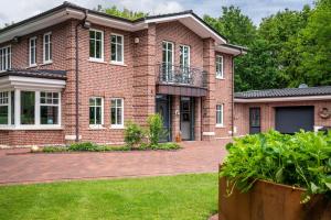 a brick house with a balcony on a yard at Ferienwohnung Kronsberg mit Sauna in Bösel