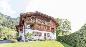 a large wooden house with a hedge in front of it at Ferme Le Coup d'Oeil in Taninges