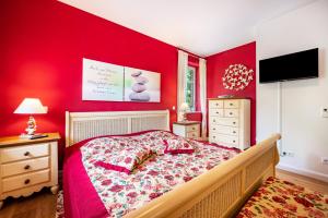 a bedroom with a red wall with a bed and a television at Ferienwohnung Kronsberg mit Sauna in Bösel