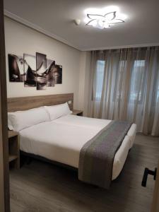 a bedroom with a large white bed and a window at Pensión del Norte in Oviedo