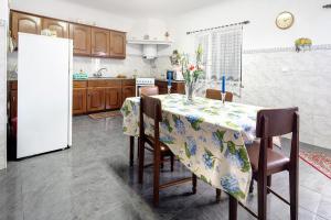 a kitchen with a table with chairs and a refrigerator at Casa das Hortênsias in Raminho