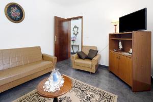a living room with a couch and a tv at Casa das Hortênsias in Raminho