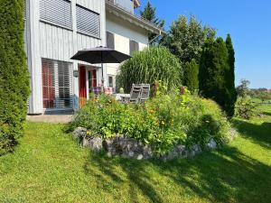 a house with a table and an umbrella in a garden at Sonnenhang in Sigmarszell