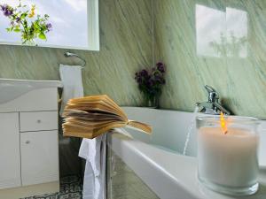 a candle sitting on a bathroom sink with a bath tub at Meadow Cottage in King's Lynn +24 photos