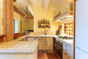 a large kitchen with yellow walls and white appliances at Le Patio in Velleron