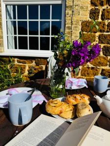 a table with a plate of pastries and flowers on it at Meadow Cottage in King's Lynn