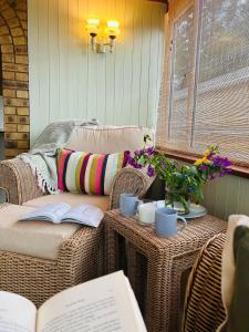 a porch with a couch and a table with books at Meadow Cottage in King's Lynn