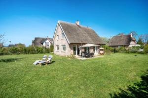 an old house with two chairs on a grass field at Reethaus Meerferien in Poseritz