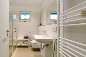 a white bathroom with a sink and a toilet at Seeschwalbe in Olpenitz +15 photos