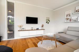 a living room with a couch and a tv on a wall at Reethaus Meerferien in Poseritz