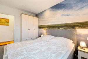 a bedroom with a bed with a painting on the wall at Seeschwalbe in Olpenitz