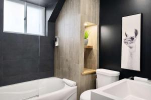 a bathroom with a tub and a toilet and a sink at Le Wolfe - 2 Bedrooms - 2 min Falls - Free Parking in Boischâtel