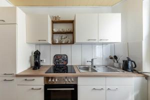 a kitchen with white cabinets and a sink at Fewo45 in Homberg