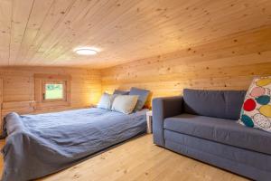 a bedroom with a bed and a couch in a room at Chalet 5 personnes, proche canal in Landeleau
