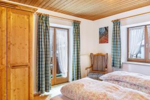 a bedroom with two beds and a chair and windows at Ferienwohnung Alpspitze in Grainau