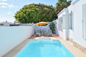 a swimming pool with chairs and an umbrella on a building at Villa Rústica con piscina privada in Tías