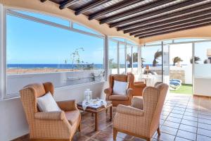 a living room with chairs and a table and windows at Villa Rústica con piscina privada in Tías