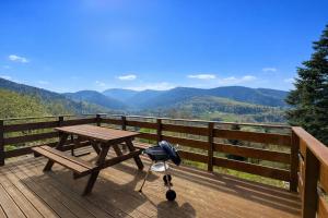 a picnic table on a deck with a view of mountains at la brume des cimes in Bussang