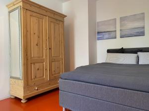 a bedroom with a bed and a wooden cabinet at Falterweg in Immenstaad am Bodensee
