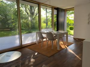 a dining room with a table and chairs and large windows at Falterweg in Immenstaad am Bodensee