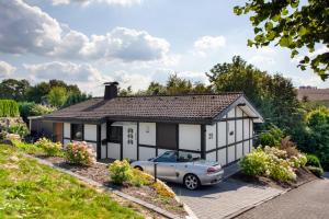 a house with a car parked in front of it at Ferienhaus Sauerland am Hennesee in Meschede