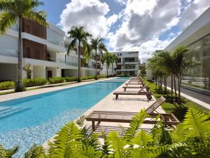 a swimming pool with chaise lounges and palm trees at Sol de Arena Beachfront, Las Terrenas in Las Terrenas