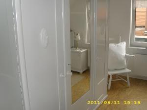 a white room with a chair and a mirror at Fennas Ferienwohnungen - Hanne in Dornumersiel